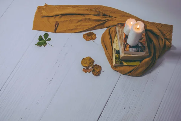 Autumn, moody books reading with warm candle aromatherapy brown colours and white floor, vintage background