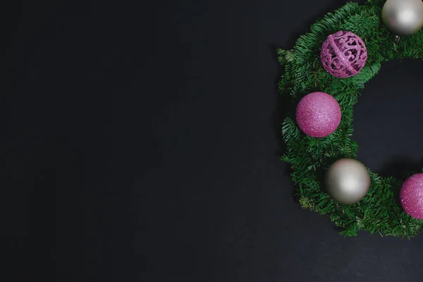 Pink and white baubles, christmas wreath on black background, ball decorations