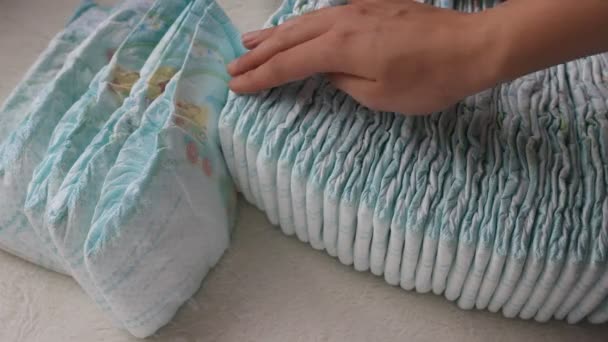 Fille tient sa main dans une pile avec des couches pour bébés, gros plan — Video