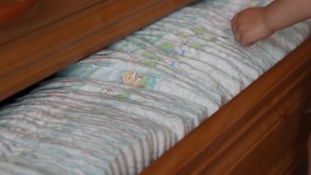 A small child takes out a baby diaper from the dresser, close-up — Stock Video