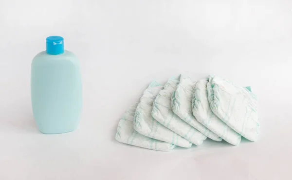 Pañales para bebés sobre fondo blanco y champú para bebés —  Fotos de Stock