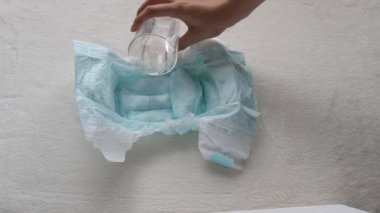 Kız bebek bezi bir bardaktan su dökülen ve peçete, yakın çekim, çocuk bezi ve su mendil