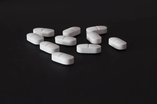 Kilka tabletek na czarnym tle, antybiotyk — Zdjęcie stockowe