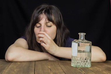 Bir kız içecekler alkol şarap-cam masaya bir şişe alkol, siyah bir arka plan ile