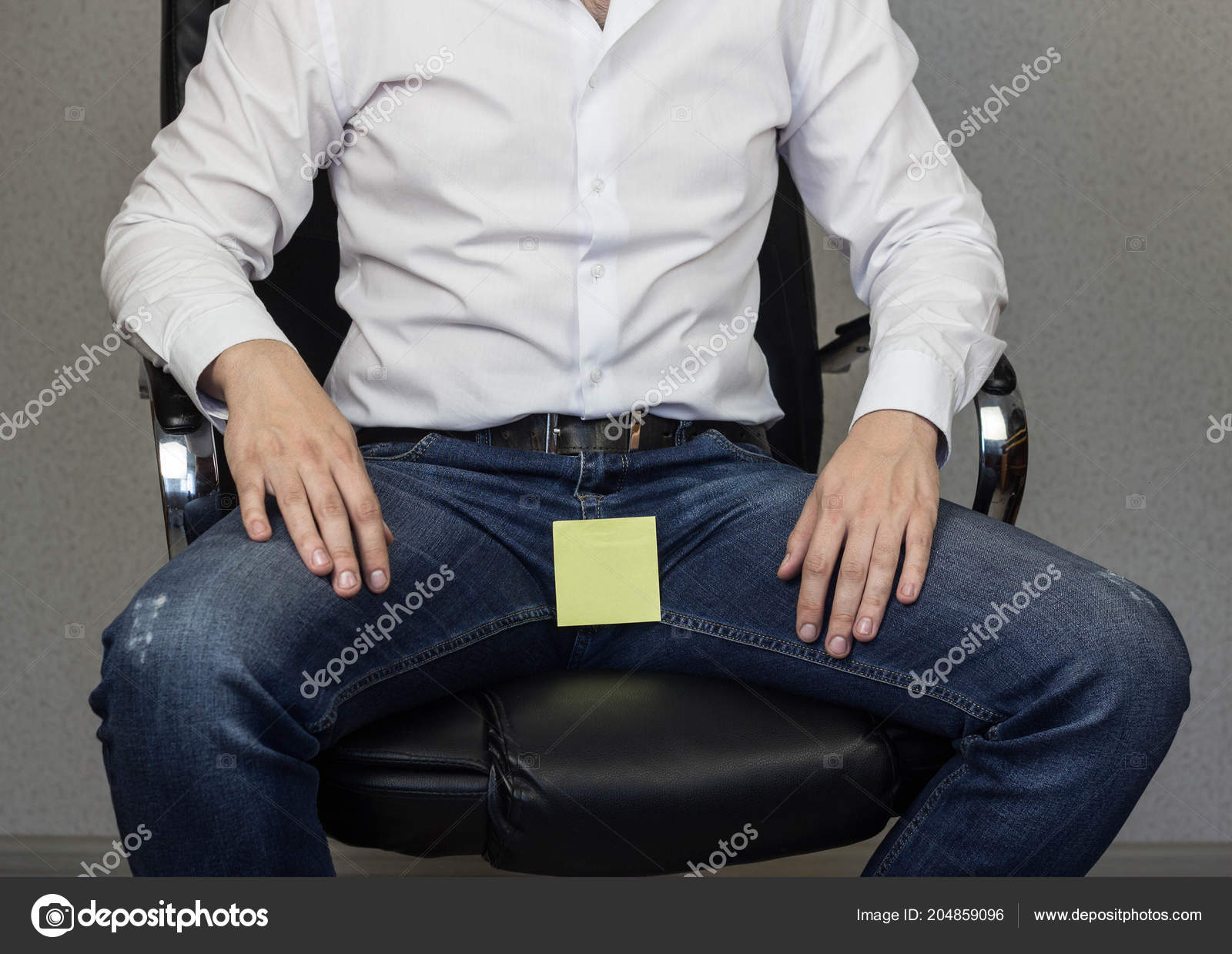 A man is sitting in an office chair, on the crotch and groin is