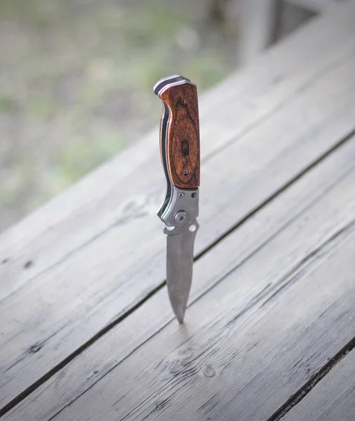 Folding knife stuck in a wooden table, close-up