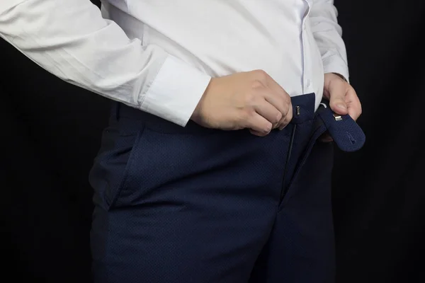 Un hombre gordo con una camisa blanca y pantalones no puede sujetar sus pantalones, sobrepeso, primeros planos — Foto de Stock