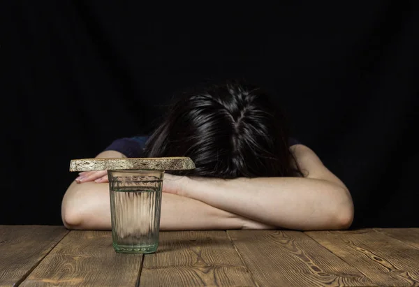 Egy pohár vizet és egy darab kenyeret, a lány fekszik a táblázat- és lapachet, fekete háttér, bánat — Stock Fotó