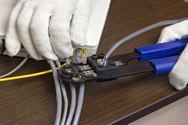 A man is squeezing a chip on a network cable, a modem, the Internet, a close-up — Stock Photo, Image