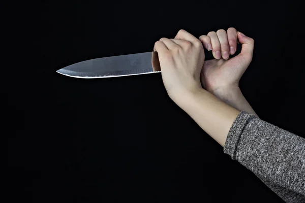 Hand of a girl with a knife on a black background, close-up, assault