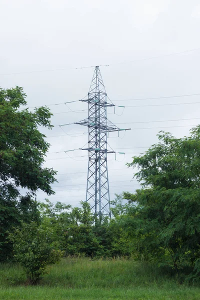 Soporte de metal de alta tensión, derrick eléctrico contra el cielo, bosque —  Fotos de Stock