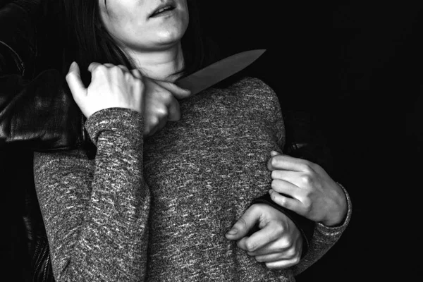 Man holding a knife at the girl's throat, black background, black and white — Stock Photo, Image