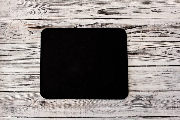 Black computer rug on a white wooden background
