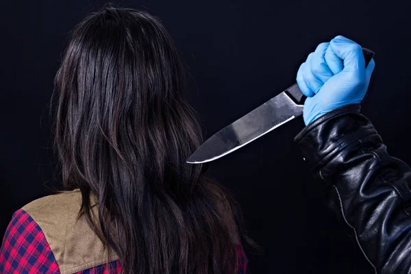 A férfi kezét kesztyű késsel hinták egy lány, egy fekete háttér — Stock Fotó