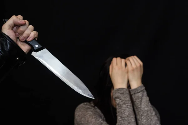 A férfi kezében egy késsel, a háttérben egy lány sír, a fekete háttér — Stock Fotó