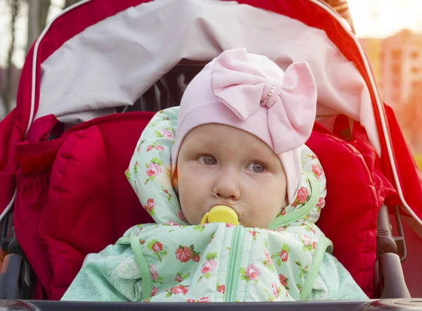 Little girl sitting in stroller with pacifier, sunset, close-up — Stock Photo, Image
