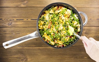 Haşlanmış sebzeler bir kızartma tavası, ahşap arka plan, yakın çekim karıştırma kız