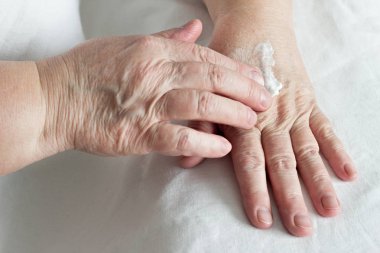 sürtünme el kremi, beyaz arka plan, yakın çekim yaşlı kadın