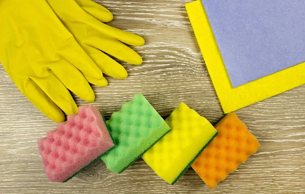 Yellow gloves and sponges for washing on a wooden background — Stock Photo, Image