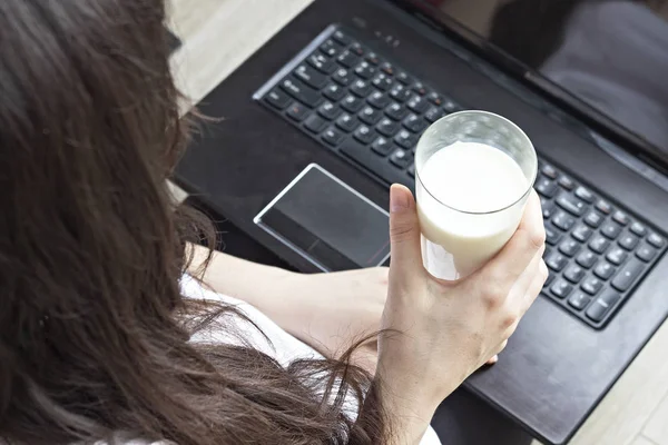 Chica morena sosteniendo la leche en un vaso, portátil, comida sana, primer plano — Foto de Stock