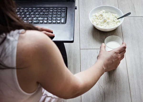 Chica con laptop, un vaso de leche y un plato con requesón, morena — Foto de Stock