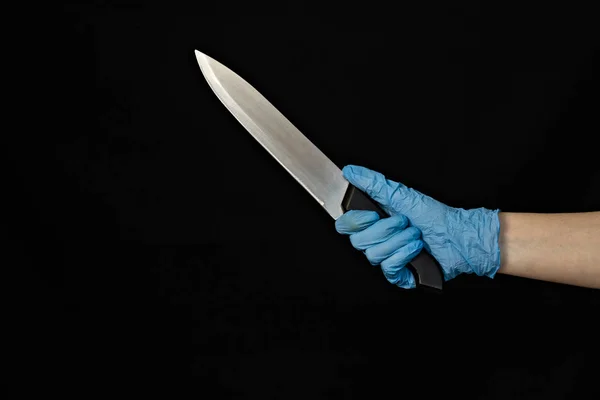 검은 배경에 칼으로 푸른 의료 장갑에 있는 여자의 손 클로즈업 — 스톡 사진
