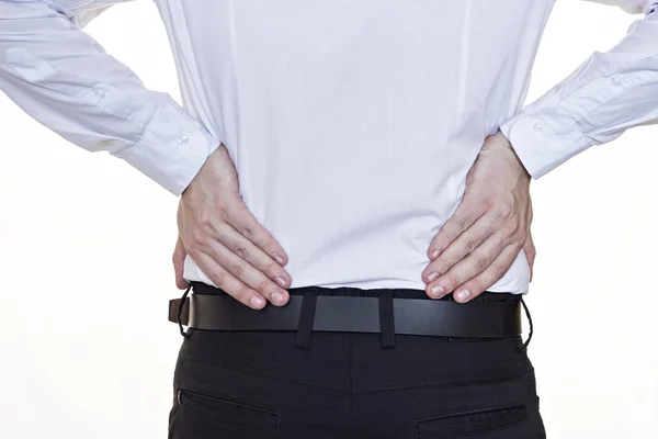 Un hombre con una camisa blanca se aferra a la parte inferior de la espalda, dolor de espalda, fondo blanco —  Fotos de Stock