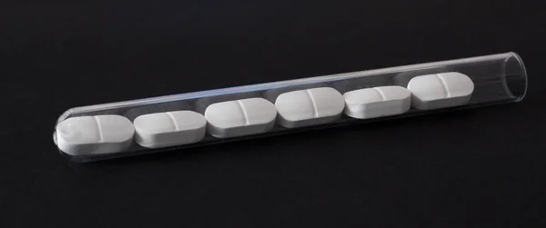 Pills in a test tube on a black background — Stock Photo, Image