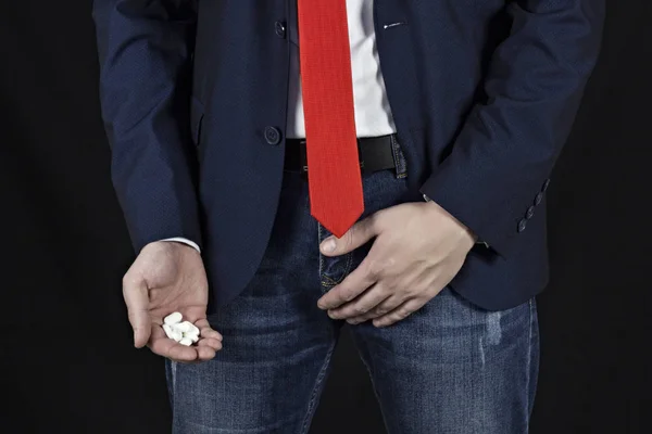 Empresário segura uma virilha, um punhado de comprimidos na mão — Fotografia de Stock