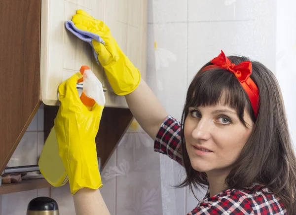 Uma menina de luvas amarelas lava o armário na cozinha, close-up — Fotografia de Stock