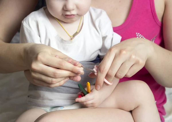 Niña madre se corta las uñas en las manos de una niña —  Fotos de Stock