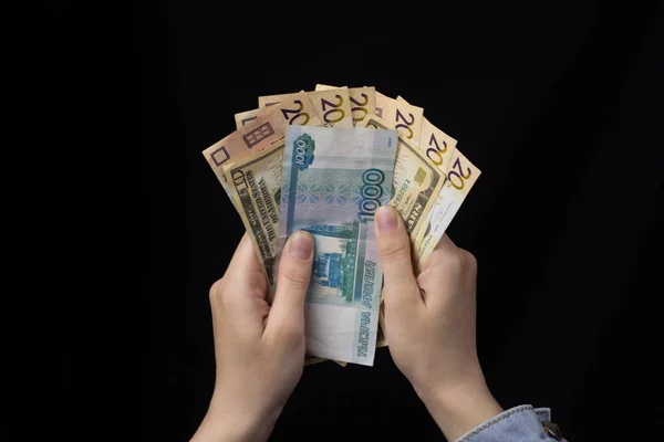 Дівчина в руках тримає гроші, євро, рублі та долари, чорний фон, крупним планом — стокове фото