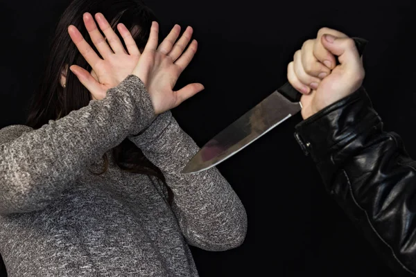 ナイフで人の手、少女は、彼女の手は、黒の背景の犯罪で顔を覆った — ストック写真