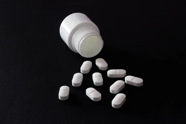 Tabletki na czarnym tle z słoik — Zdjęcie stockowe