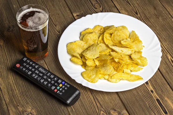 Chips con control remoto de cerveza y TV sobre fondo de madera — Foto de Stock