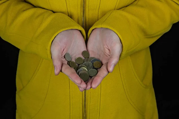 Dziewczyna w żółtym fartuchu posiada monetę w jej ręce na czarnym tle — Zdjęcie stockowe