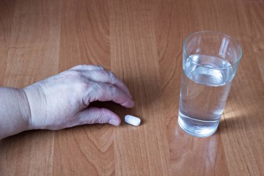 Yaşlı bir kadın el alır bir hap, bir bardak su, bir yakın çekim