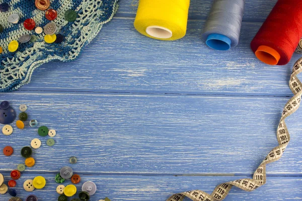 Boutons fil ciseaux centimètre ruban sur un fond en bois bleu — Photo