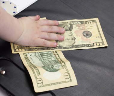 Çocuğun elini tutar para dolar siyah bir arka plan üzerinde yakın çekim, on dolar