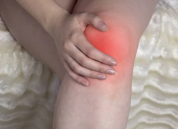 The girl holds on to the knee, the red knee, arthrosis of the knee, close-up — Stock Photo, Image