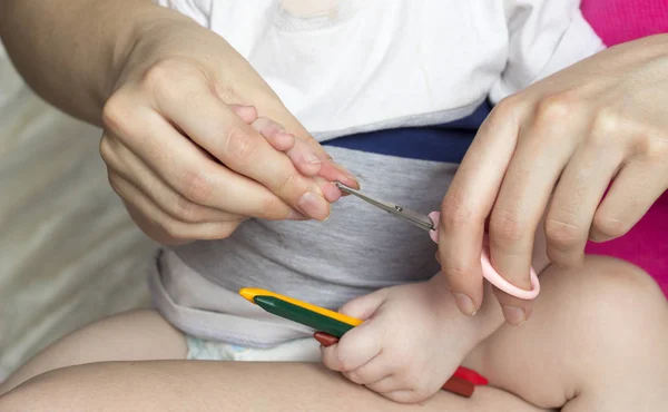 Moeder knipt haar nagels in de handen van een klein meisje, close-up — Stockfoto