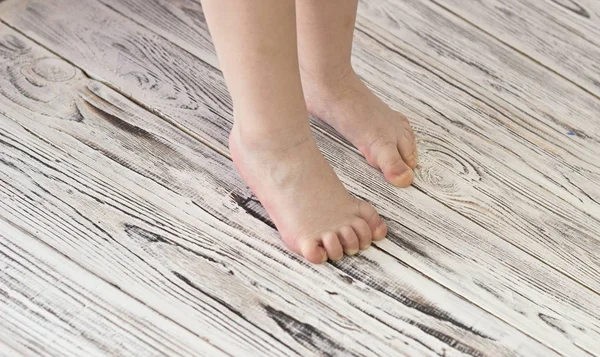 Patas de bebé sobre un fondo de madera blanco —  Fotos de Stock