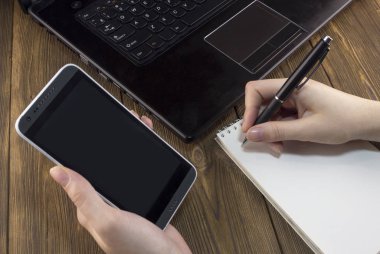 Ahşap arka plan üstünde Laptop telefon el not etmek