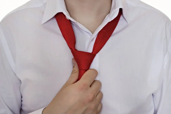 Um homem com uma camisa branca e gravata vermelha segura em um empate, fundo branco, close-up — Fotografia de Stock