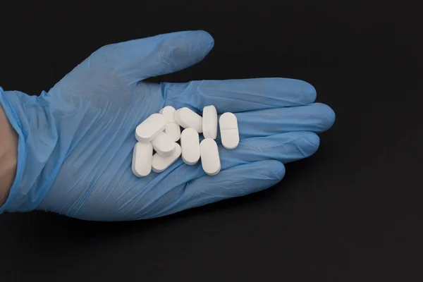 Tabletki na czarnym tle i rękawiczki medyczne — Zdjęcie stockowe