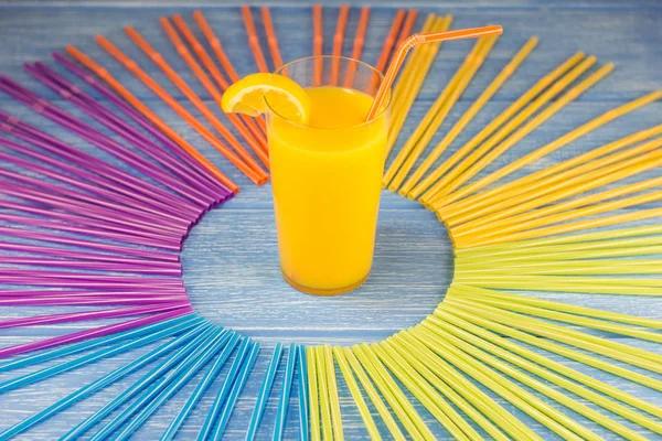 Orange juice and straws for drinking on a wooden background