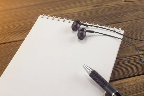 Блокнот, ручка, навушники на дерев'яному фоні — стокове фото