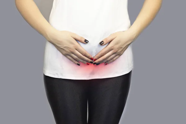 La niña se aferra a la parte inferior del abdomen, la parte inferior del abdomen es de color rojo, el plan medio — Foto de Stock