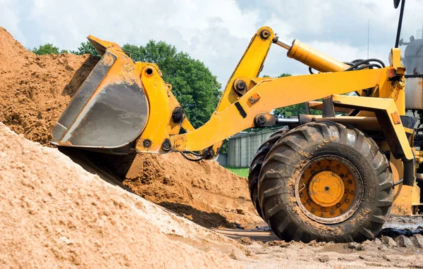 Gul traktor lastare är att plocka upp en hink med jord, mekaniska, slev med jorden — Stockfoto