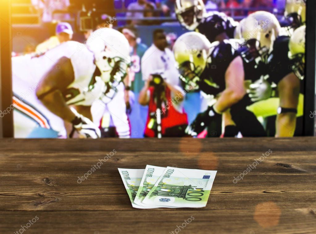 Euro money on the background of a TV on which American football is shown, betting on sports, euro and American football